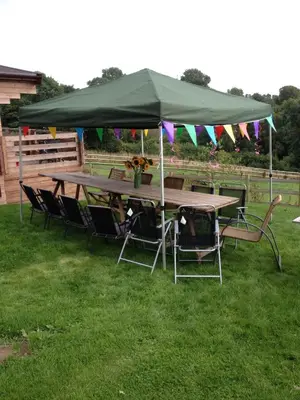 a picnic table with a green canopy on the grass at Long Mountain Centre Log Cabins in Meadowtown