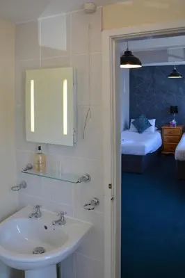 a bathroom with a sink and a bedroom with a bed at Llanerch Inn in Llandrindod Wells