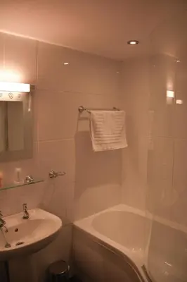 a white bathroom with a sink and a tub and a sink at Llanerch Inn in Llandrindod Wells