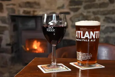 two glasses of beer on a table with a fireplace at The Llanelwedd Arms Hotel in Builth Wells