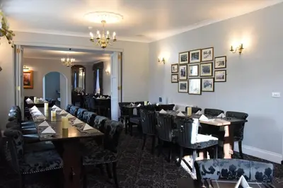 a dining room with tables and chairs and a chandelier at The Llanelwedd Arms Hotel in Builth Wells
