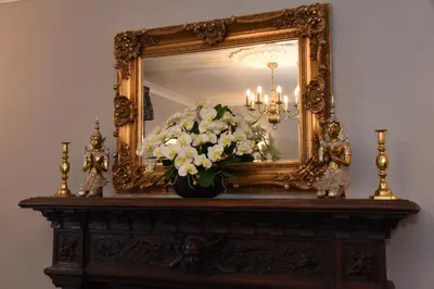 a mirror with a vase of flowers on a table at The Llanelwedd Arms Hotel in Builth Wells
