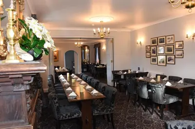 a restaurant with tables and chairs and a bar at The Llanelwedd Arms Hotel in Builth Wells
