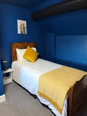 a blue bedroom with a bed with a yellow pillow at The Black Swan Inn in Leominster