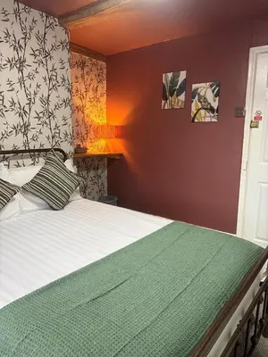 a bedroom with a bed with a green comforter at The Black Swan Inn in Leominster