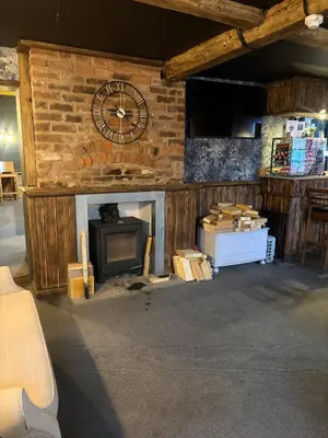 a room with a fireplace and a clock on a wall at The Black Swan Inn in Leominster