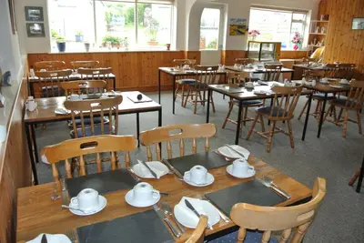 a dining room with wooden tables and chairs with dishes on them at Old Castle Farm Guest House in Brecon