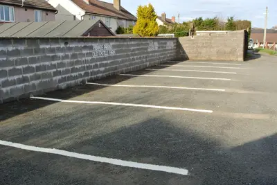 a parking lot next to a brick wall at Old Castle Farm Guest House in Brecon