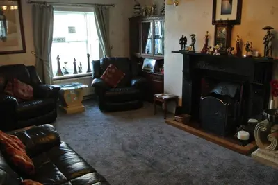 a living room with leather furniture and a fireplace at Old Castle Farm Guest House in Brecon