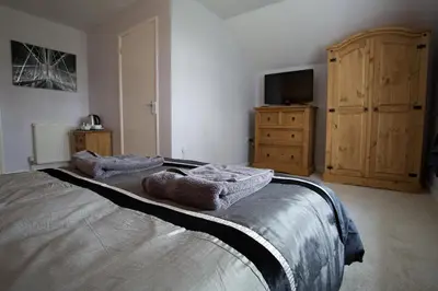 a bedroom with a bed and a tv and a dresser at Penrhosmawr in Machynlleth