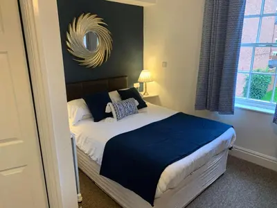 a bedroom with a bed with a mirror on the wall at Abbots Mead Hotel in Shrewsbury