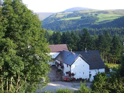 a white house in the middle of a mountain at Dee Valley Cottages in Llangollen
