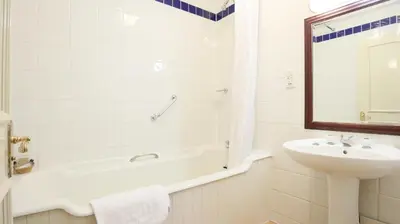 a white bathroom with a sink and a tub and a mirror at The Lion Hotel Shrewsbury in Shrewsbury