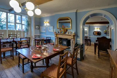 a dining room with tables and chairs and a fireplace at The Wynnstay in Machynlleth