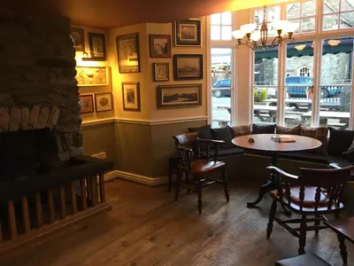a restaurant with a table and chairs and a fireplace at Plas Yn Dre in Bala