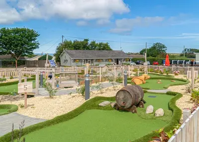 a childrens playground with a large log on the grass at Pencnwc Holiday Park in Llanllwchaiarn