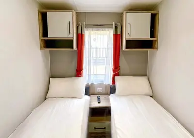 two beds in a small room with a window at Pencnwc Holiday Park in Llanllwchaiarn