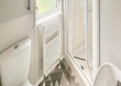 a white bathroom with a toilet and a window at Pencnwc Holiday Park in Llanllwchaiarn