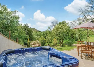 a blue pool in a backyard with an umbrella at Slate House Lodges in Towyn