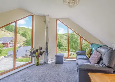 a living room with a couch and large windows at Slate House Lodges in Towyn
