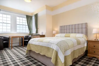 a bedroom with a large bed and two chairs at Crown Lodge in Harlech