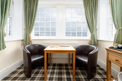 two chairs and a table in a room with windows at Crown Lodge in Harlech