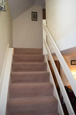 a staircase in a house with brown carpet at Ceiros Cottage in Llangammarch Wells