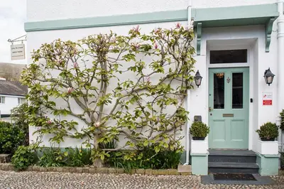 a house with a flowering tree in front of it at Llety Brynawel Guest House in Pennal