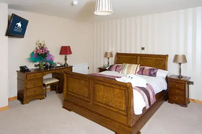 a bedroom with a large wooden bed and a desk at The Elephant & Castle Hotel in Newtown