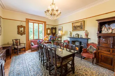 a living room with a table and chairs and a fireplace at Taldraeth - Old Vicarage Guest House in Penrhyndeudreath
