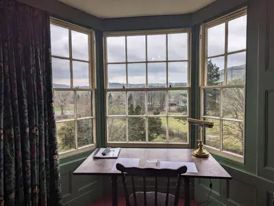 a room with a table and chairs in front of windows at Bron-Y-Graig in Corwen