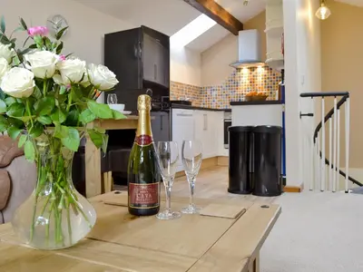a bottle of champagne and two glasses on a wooden table at Y Bwthyn Pren in Aberaeron