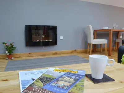 a table with a magazine and a cup on it at The Loft - Uk6210 in Llanerch-Aeron