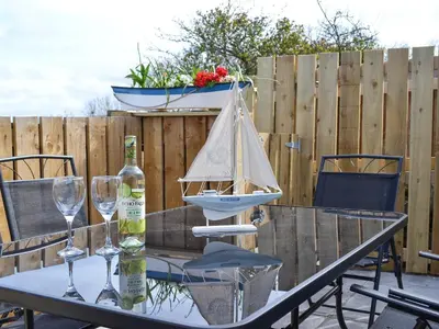a table with wine glasses and a model boat on it at Montrose in New Quay