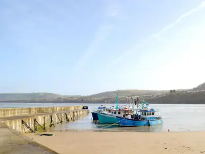 a blue boat is docked next to a pier at Montrose in New Quay