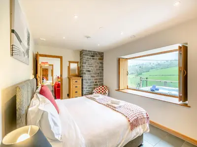 a bedroom with a bed and a large window at Wern Ddu Cottage in Pen-y-bont-fawr