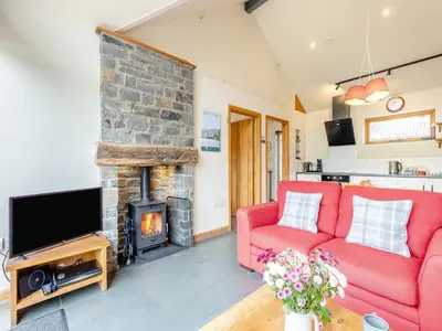 a living room with a red couch and a fireplace at Wern Ddu Cottage in Pen-y-bont-fawr