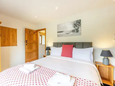 a bedroom with a large white bed with red pillows at Wern Ddu Cottage in Pen-y-bont-fawr