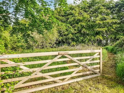 a wooden fence in the middle of a field at Tyllwyd Farmhouse in Capel Bangor