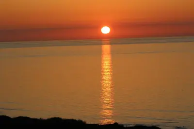 a sunset over the ocean with the sun reflecting in the water at The Pod & Cwtch luxury accommodation in Aberaeron
