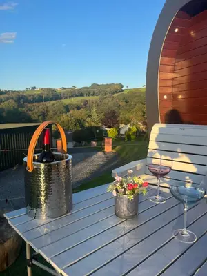 a picnic table with a bottle of wine and glasses at The Pod & Cwtch luxury accommodation in Aberaeron