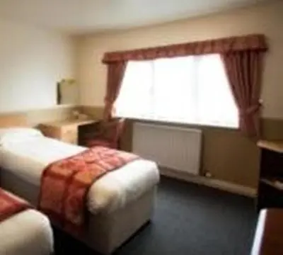 a hotel room with two beds and a window at Moreton Park Hotel in Chirk