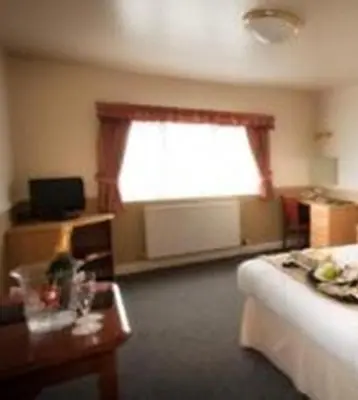 a room with a bed and a window and a table at Moreton Park Hotel in Chirk