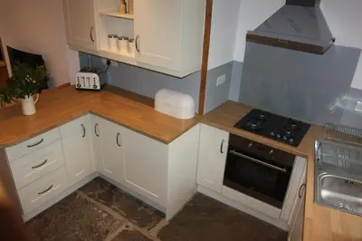a small kitchen with white cabinets and a stove at Delfryn Cottage in Rhayader