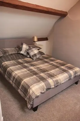a bedroom with a bed with a plaid blanket at Delfryn Cottage in Rhayader