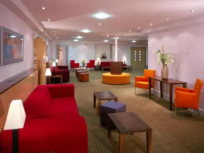 a lobby with red and orange chairs and tables at Metropole Hotel and Spa in Llandrindod Wells