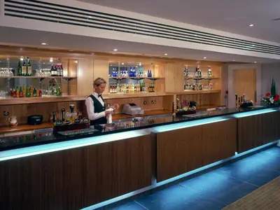 a woman standing behind a bar in a restaurant at Metropole Hotel and Spa in Llandrindod Wells