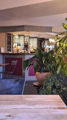 a restaurant with a table and plants in front of a bar at Y Branwen Restaurant & Rooms - Adult Only and Dog Friendly in Harlech