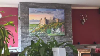 a painting of a castle is hanging on a wall at Y Branwen Restaurant & Rooms - Adult Only and Dog Friendly in Harlech