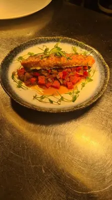 a plate with a piece of fish on a table at Y Branwen Restaurant & Rooms - Adult Only and Dog Friendly in Harlech